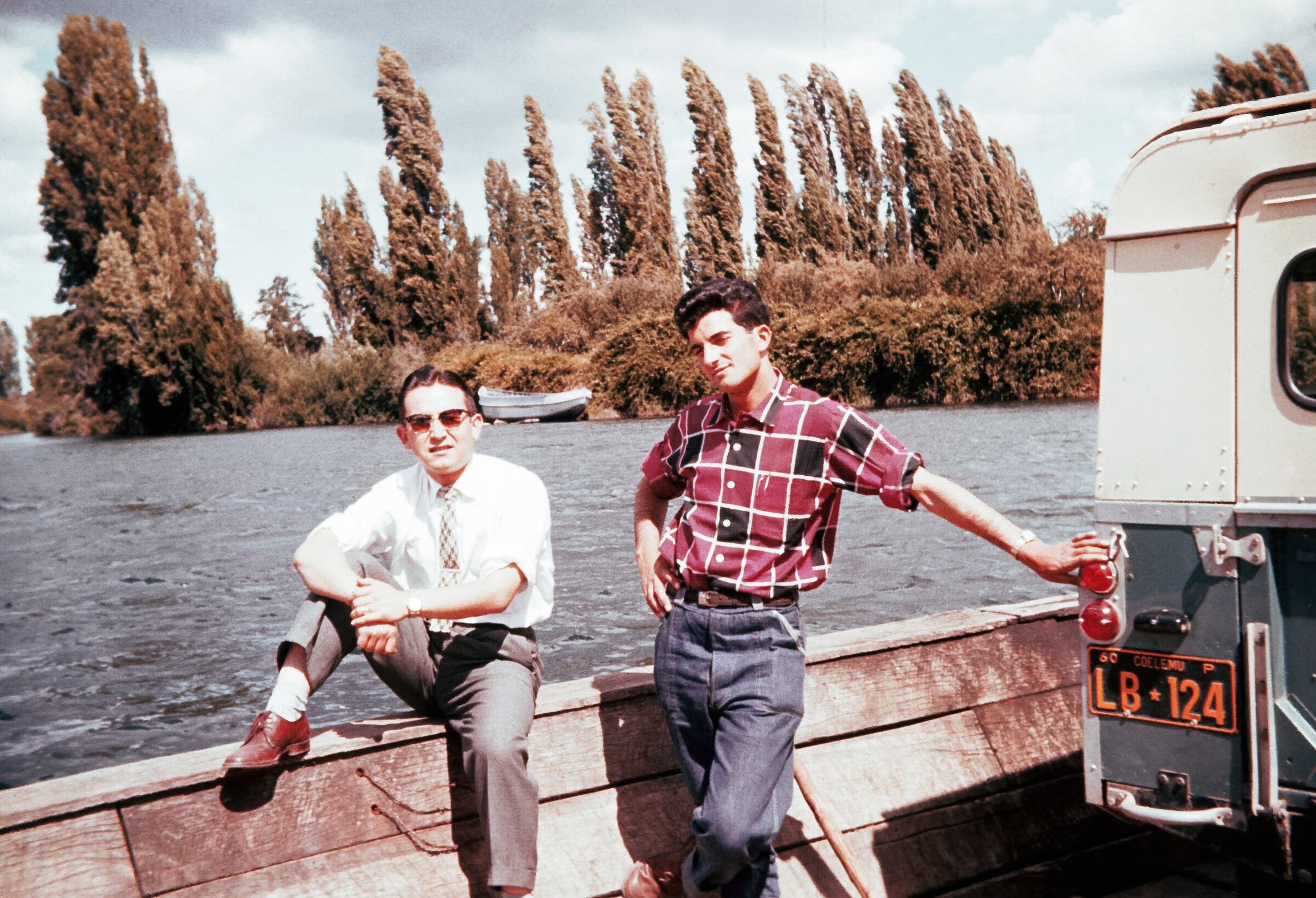 Retrato de plano entero de Francisco Rincón Gonzalez (derecha) y Yoyi Koda Rost posando de frente en un transbordador cruzando el río Bueno