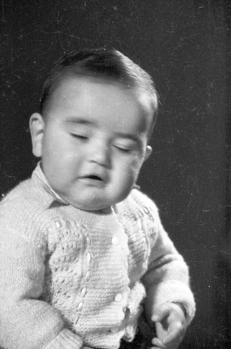 Retrato de estudio de Plano medio de Bebé sentado con chaleco de lana, con los ojos medio cerrados