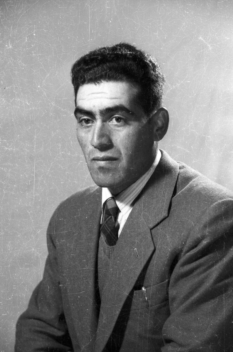 Retrato de estudio de Plano medio de un hombre posando de Medio perfil. Lleva una lapicera en el bolsillo del pecho de su Traje