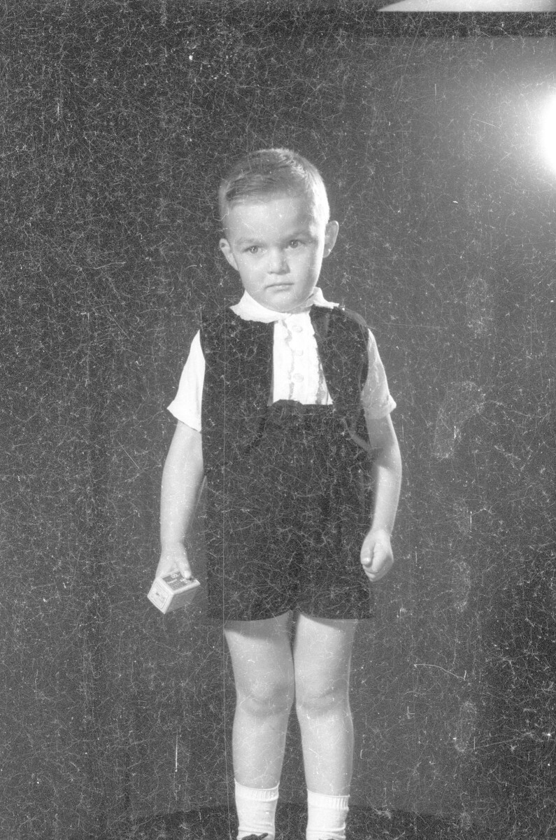 Retrato de estudio de Plano medio largo de un niño posando parado con una caja en sus manos. Se encuentra parado sobre una mesa