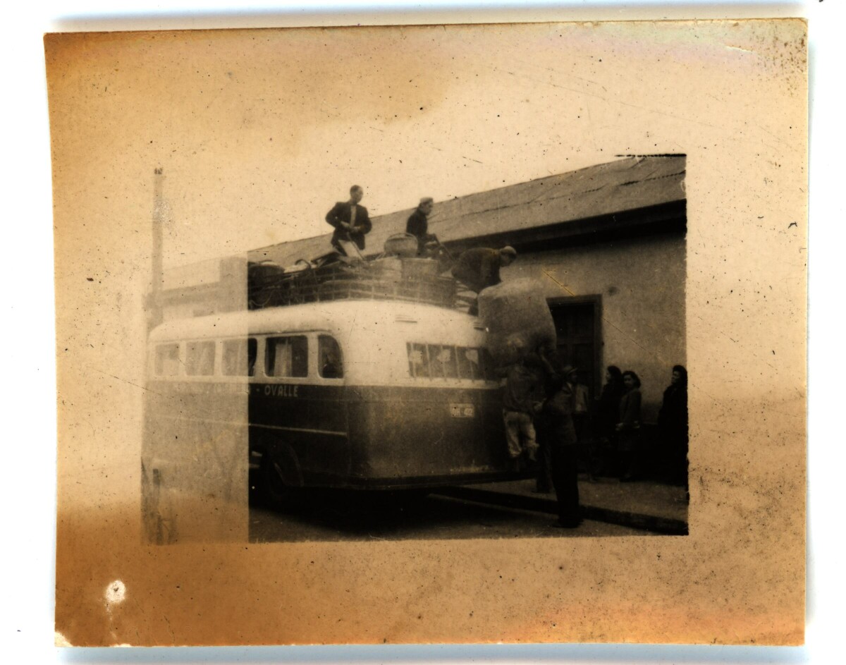 -Personas cargando artículos en un minibús que lee --OVALLE-- . Hay personas esperando a subirse y gente arriba de este, cargando los bultos-